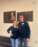 Tim Chiarolanza standing with a woman beside memorial plaques at a Lycoming College event
