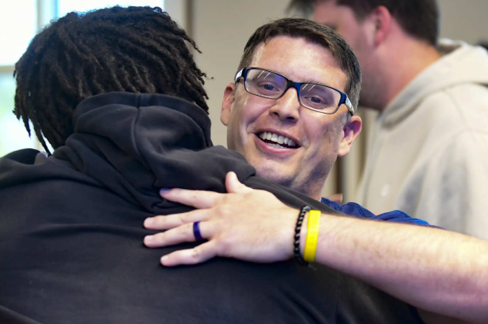 Tim Chiarolanza smiling as a friend hugs him